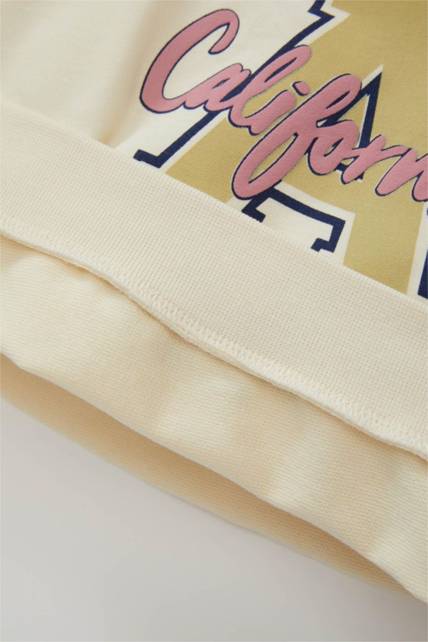 طفلة صغيرة بيج فاتح سويت شيرت بناتي بطبعة شعار قصة عادية